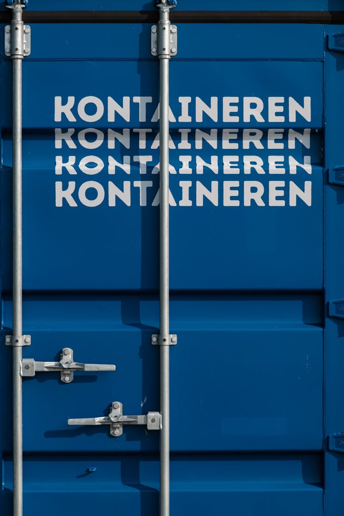 services-01 Detailed view of blue shipping container with text 'KONTAINEREN' and metal locks.