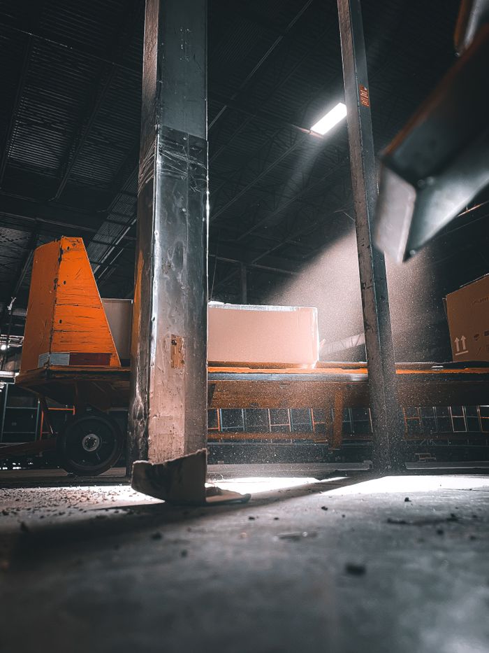 gallery-3 Sunlight streaming through warehouse beams onto industrial equipment in a factory setting.