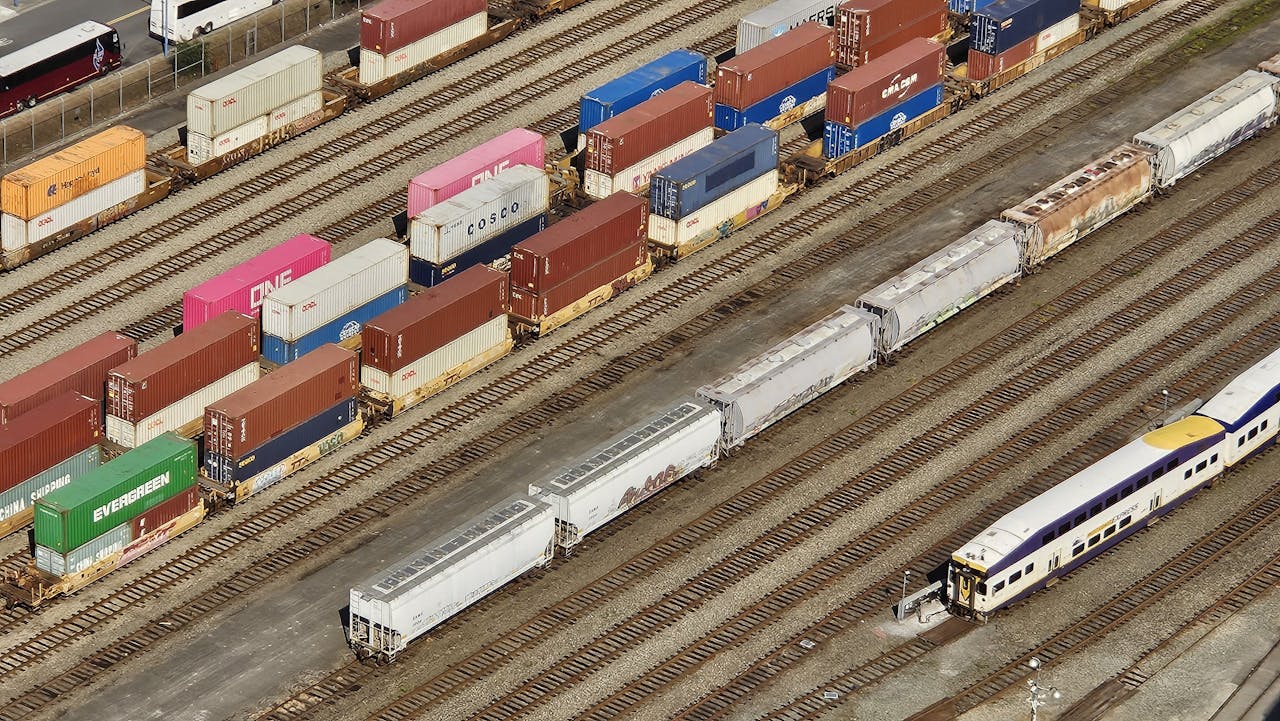 Aerial shot showcasing colorful freight containers on train tracks in a busy transportation yard.