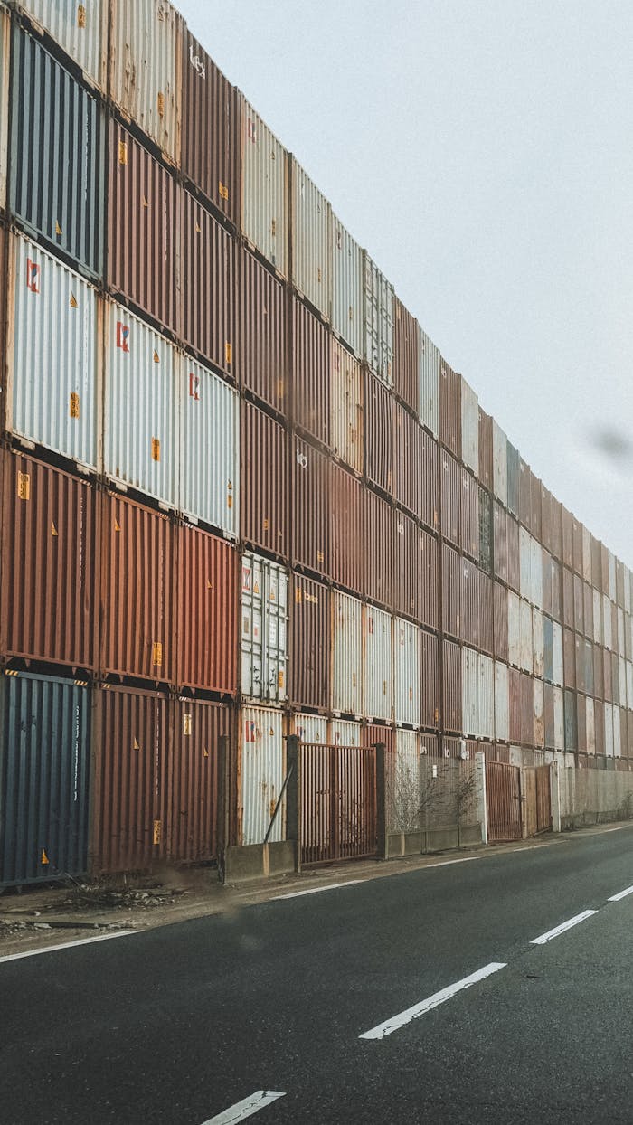 services-01 High-rise stack of shipping containers along an industrial road in foggy weather.