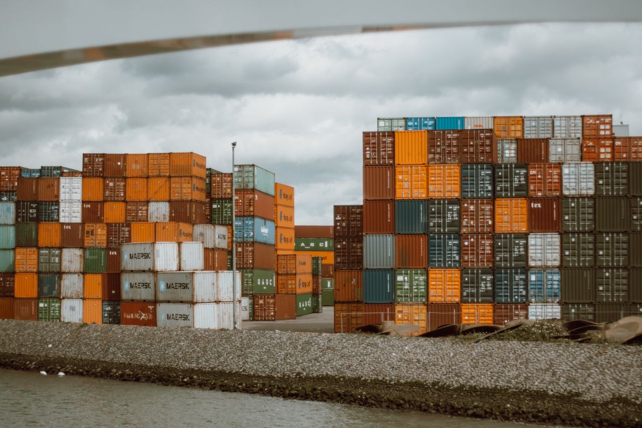 services-img Colorful shipping containers stacked in Rotterdam harbor, under overcast skies.