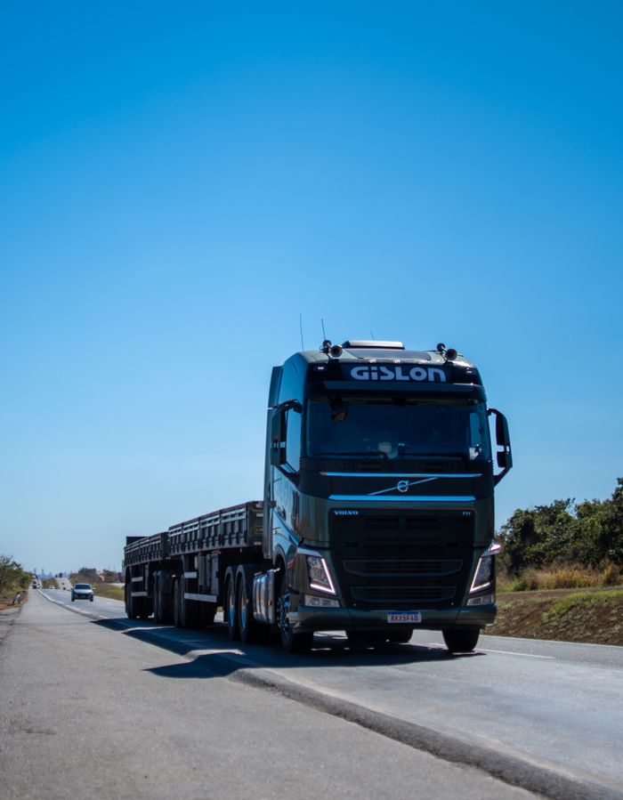gallery-2 A black truck travels on a sunny highway in Brazil under clear blue skies.